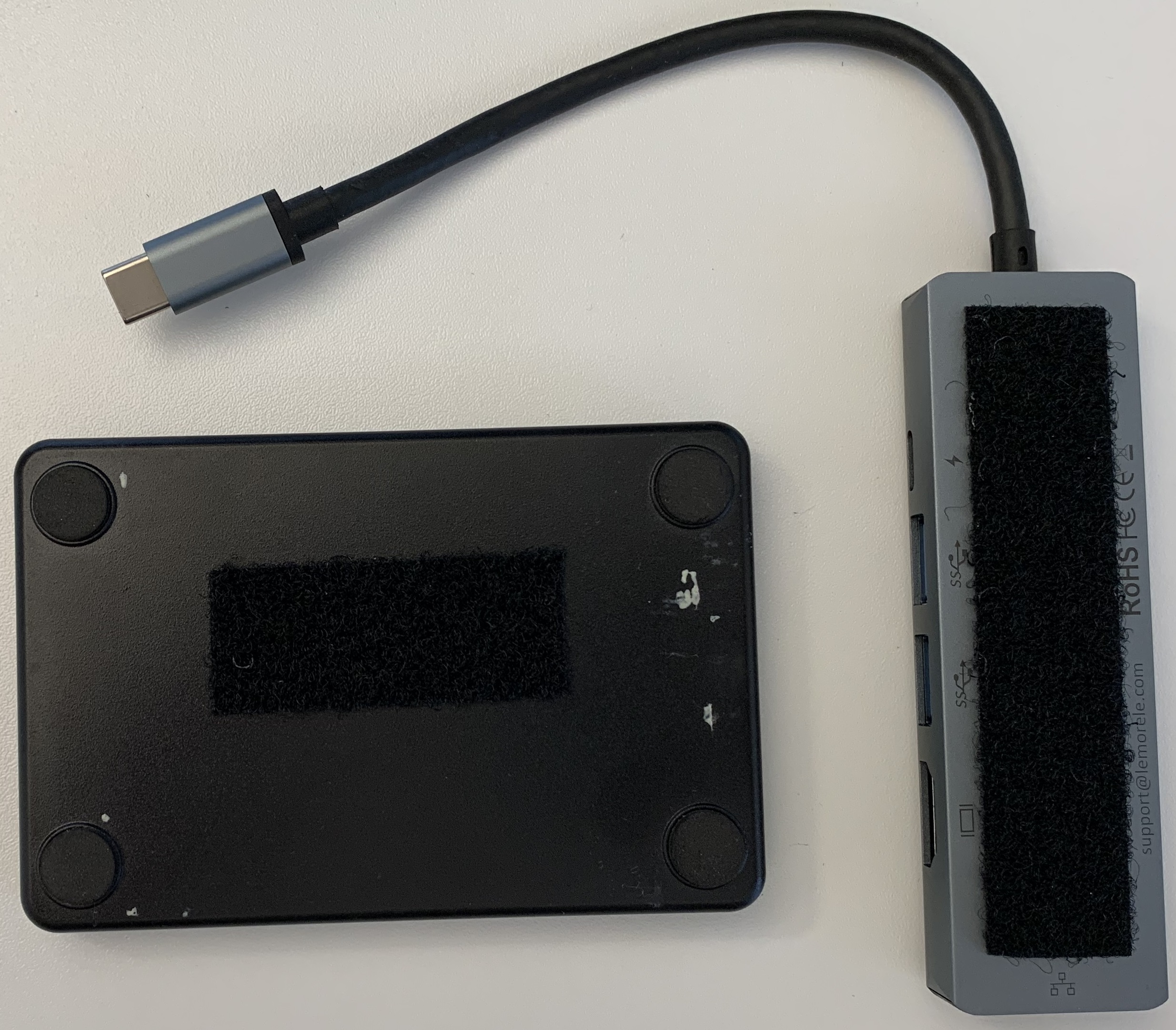 The USB-C dongle is attached under the enclosure, the cable routed through the central hole